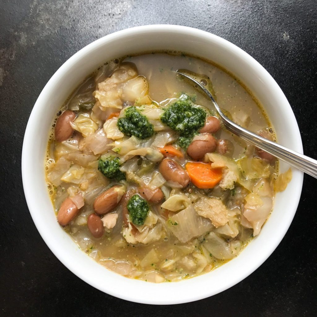 A bowl of soup with beans and vegetables.