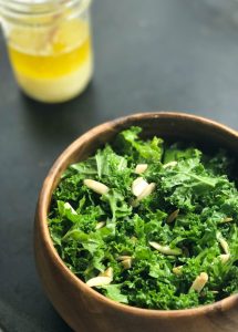 kale salad with lemon dressing topped with almonds