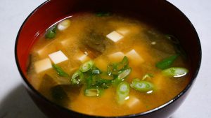 A miso soup with tofu and green onions.