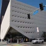 A crowd of people standing in front of a large white building.