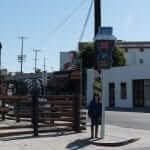 A person is standing on a sidewalk next to a street sign.