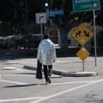 A man in a jacket crossing a street.