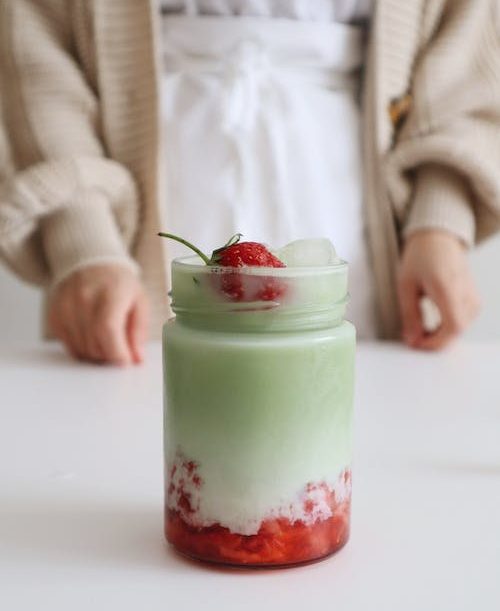 Strawberry ice cream with matcha syrup in a jar.