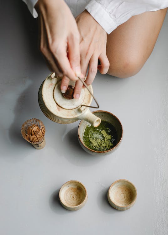 A woman pouring matcha syrup into a bowl.