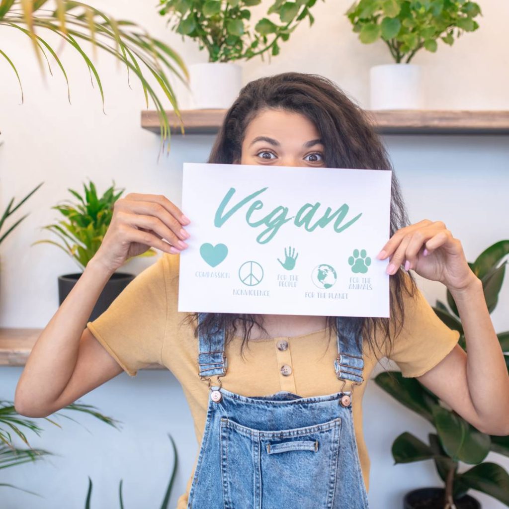 Woman wearing orange shirt holding a vegan sign