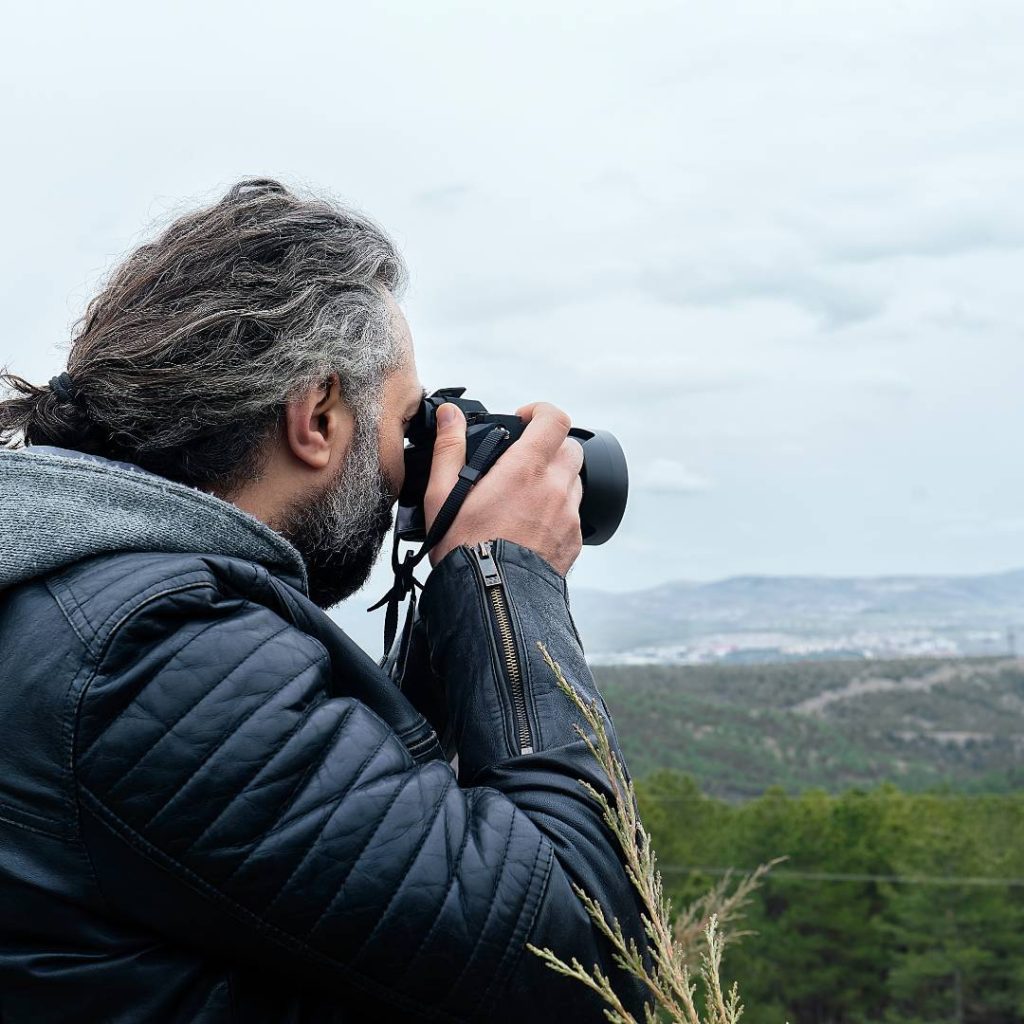 Man taking photo with full frame camera from up on the hill