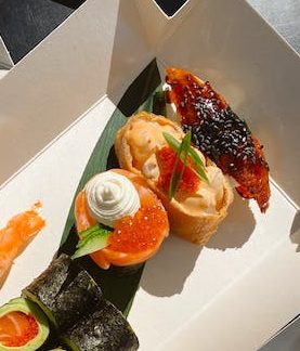 A variety of sushi in boxes on a table.