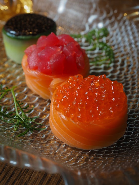 A glass plate with a salmon and a cucumber on it.