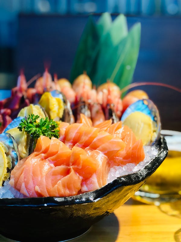 A bowl of sushi grade sashimi and seafood on a table.