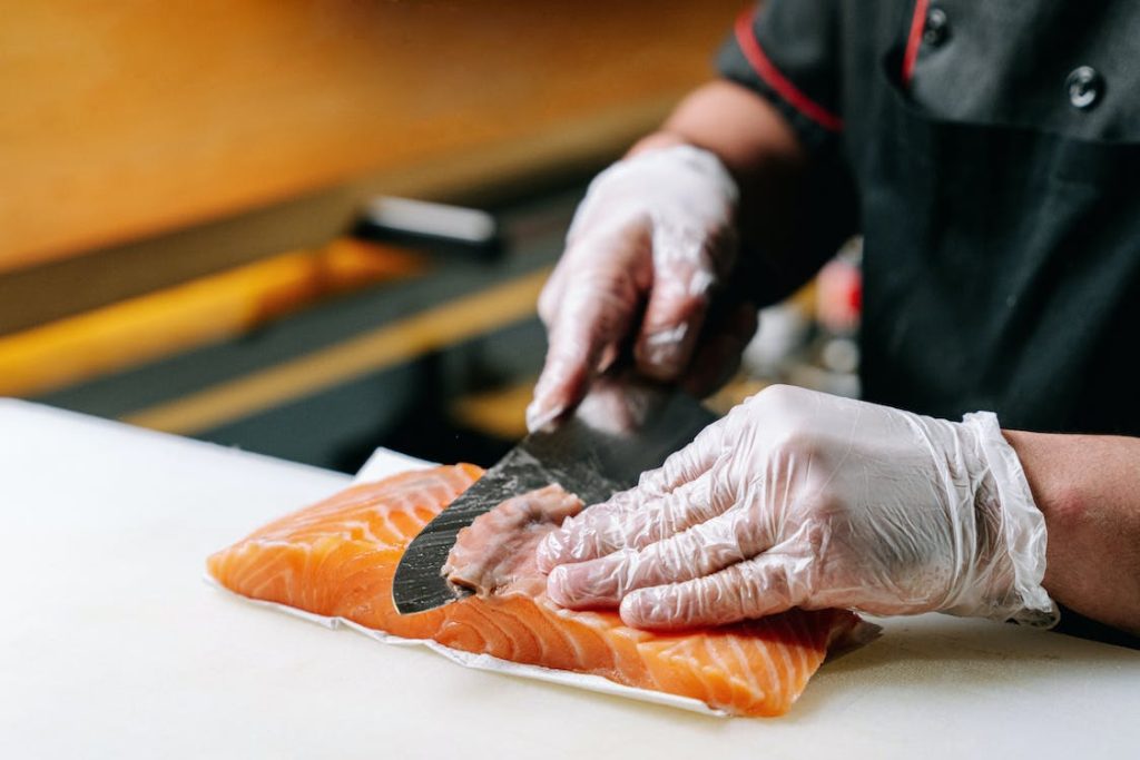 A chef is slicing a sushi grade piece of salmon.