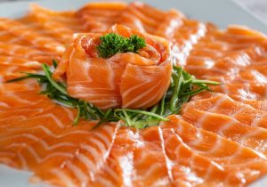 Sliced sushi grade salmon on a white plate.