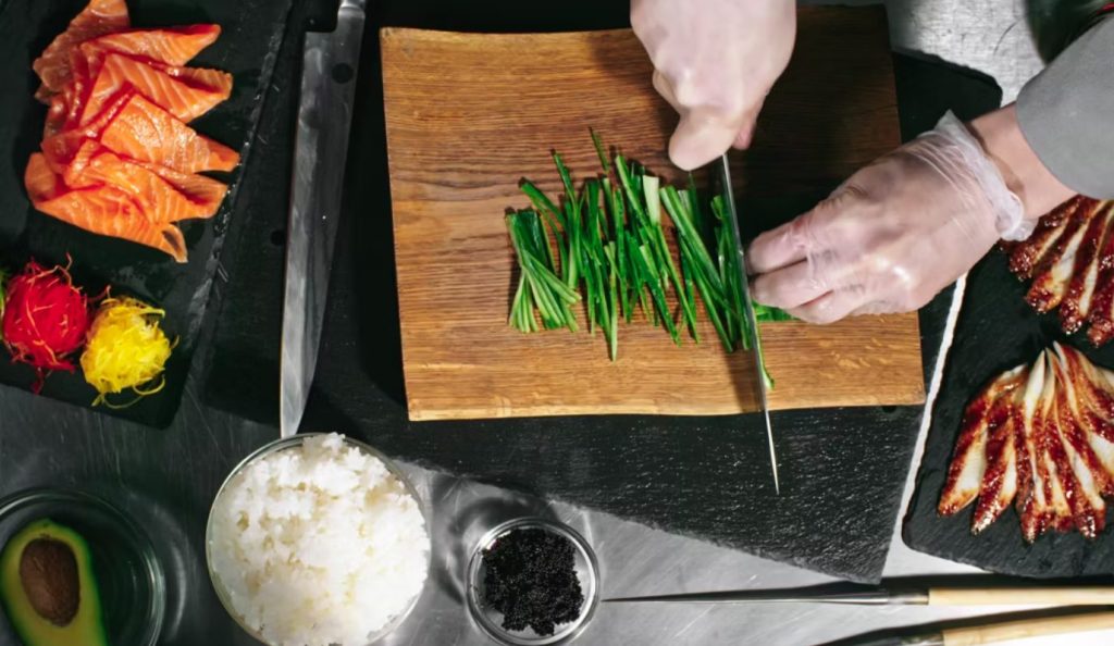 A chef is preparing Sushi Bake on a cutting board.