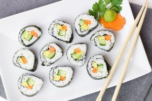 Japanese sushi roll without a mat served with vegetables on a white plate.