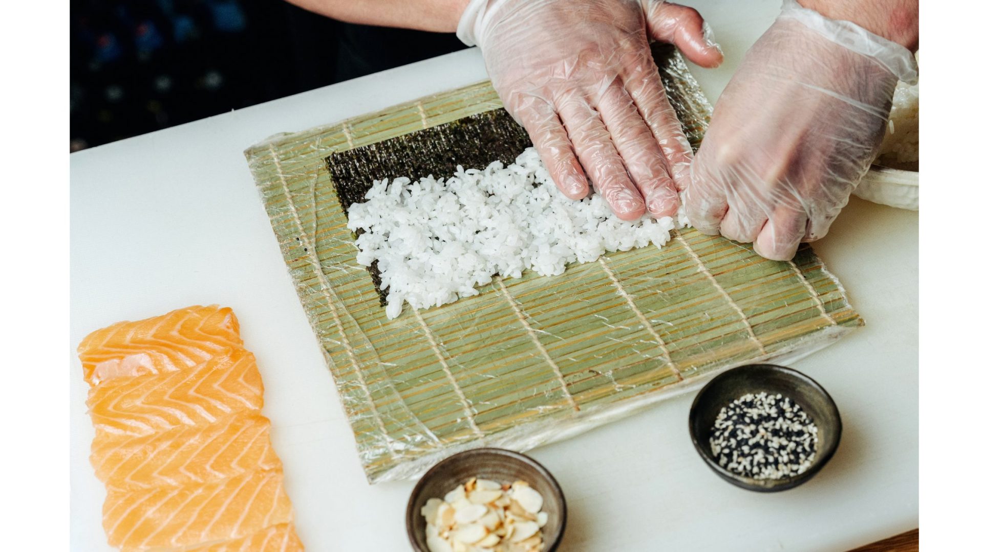 A person is preparing sushi on a bamboo mat.