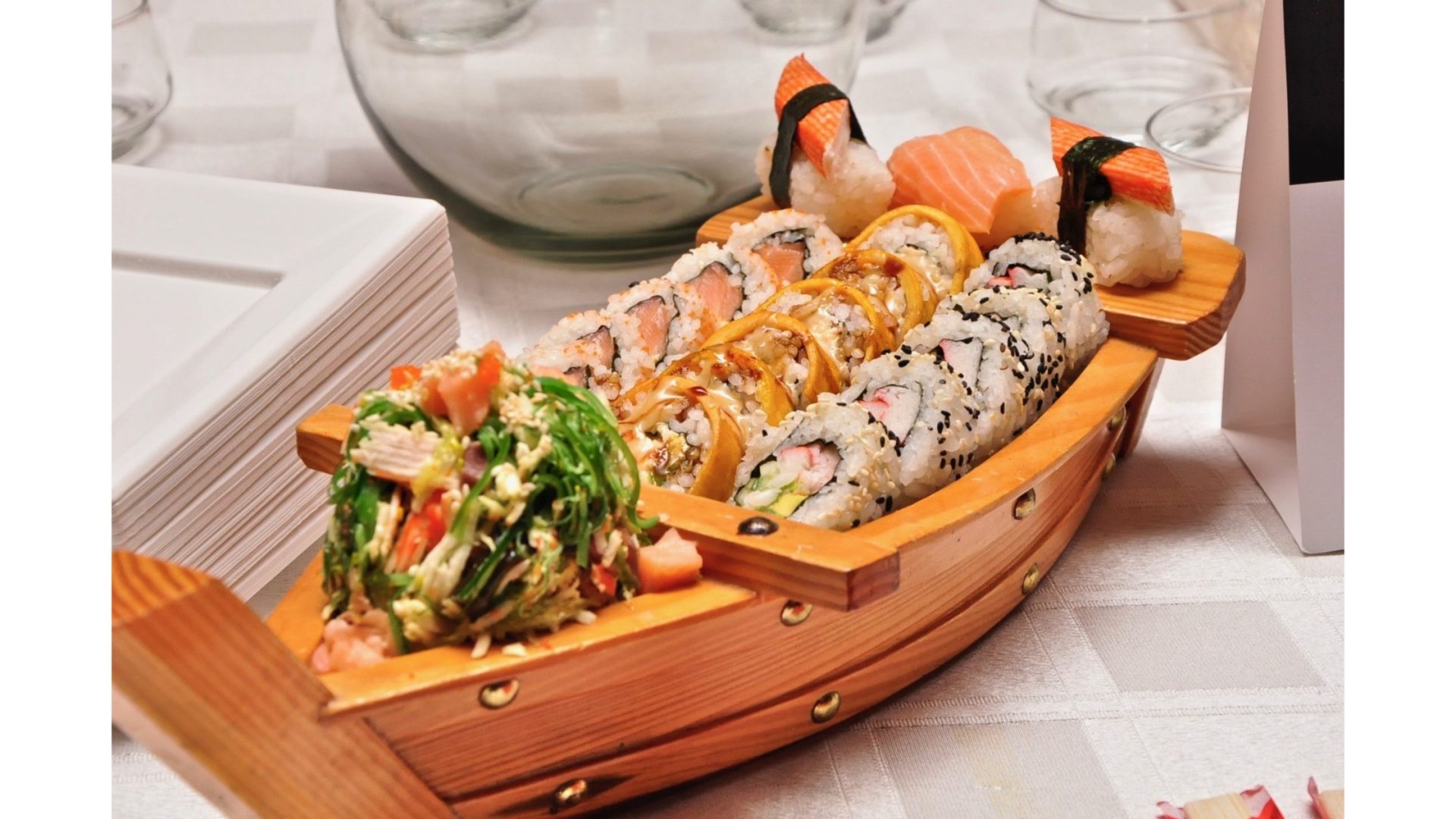 A wooden boat filled with sushi and sushi rolls.