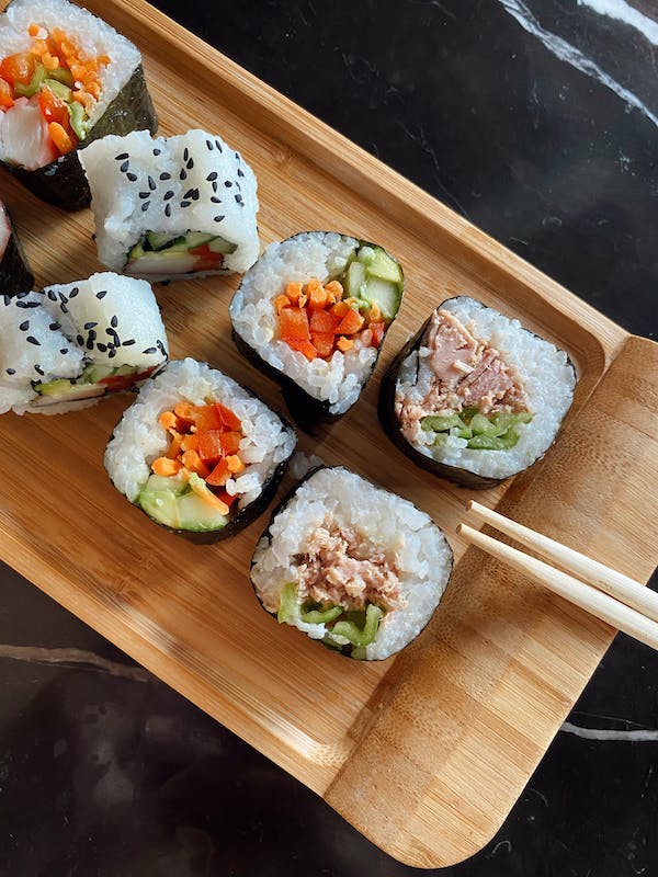 Traditional Japanese sushi rolls served on a wooden tray with chopsticks.