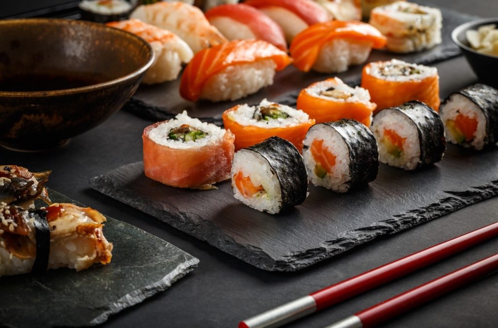 Low-calorie Japanese sushi on a slate plate with chopsticks.