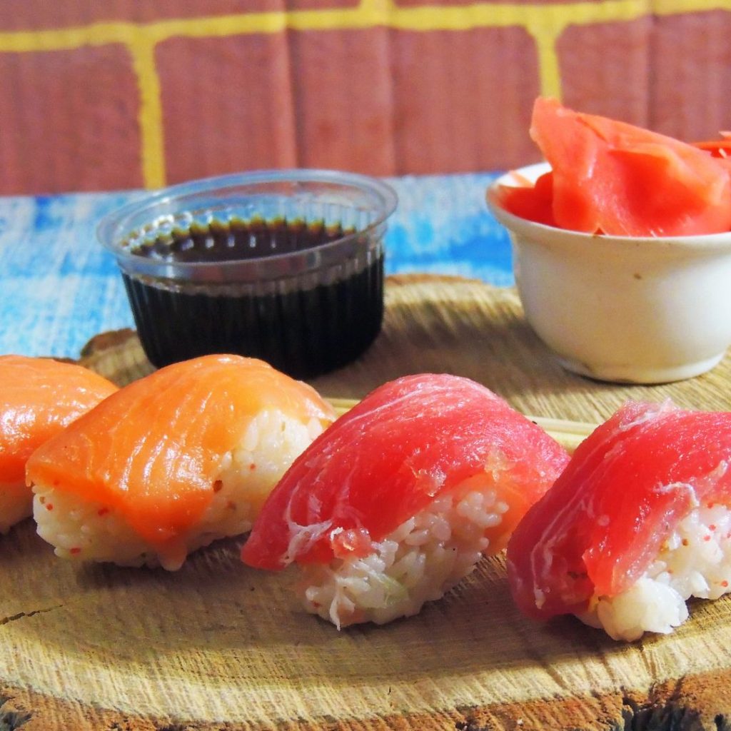 Sushi on a wooden board with a dipping sauce.