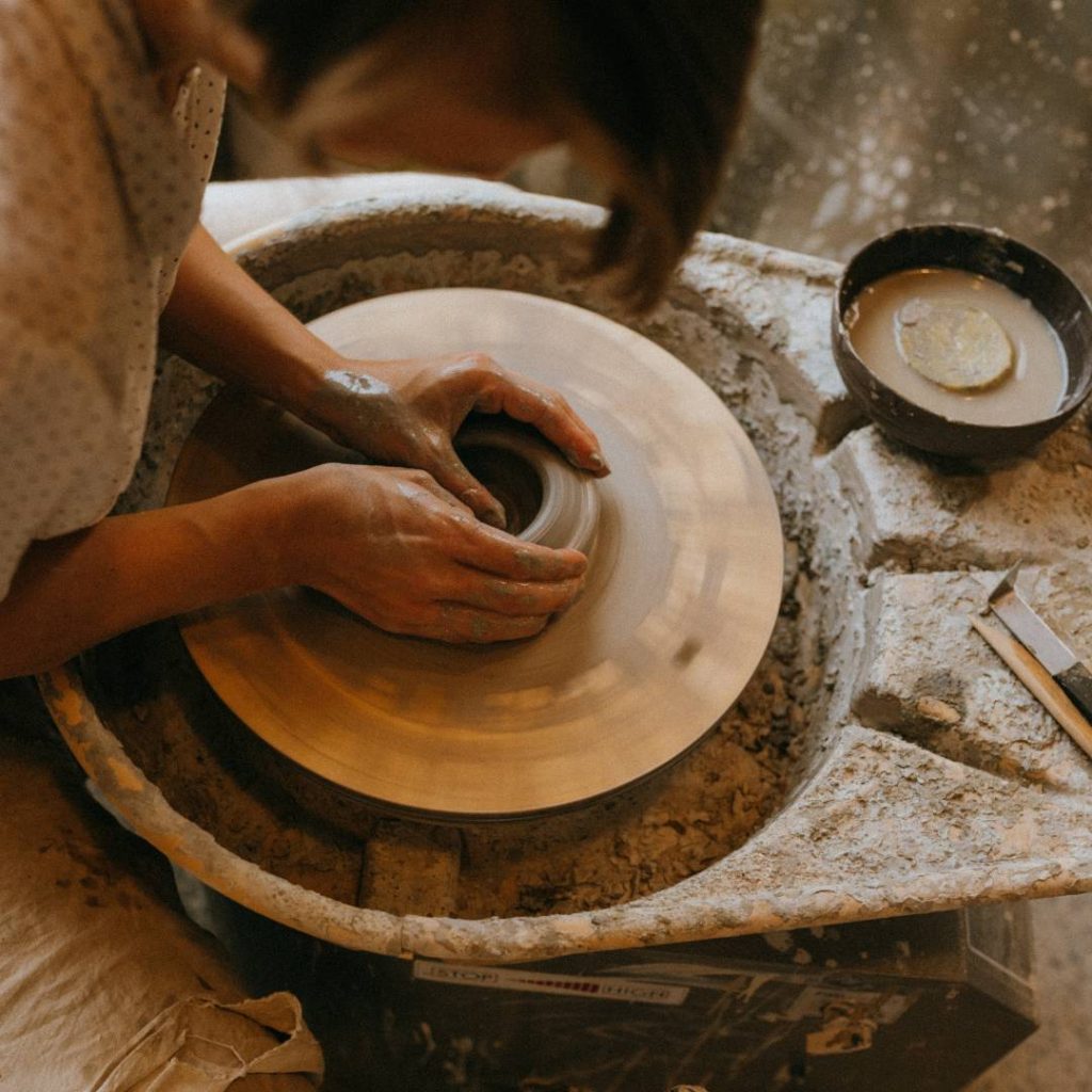 A woman is making a bowl on a pottery wheel in Okinawa.