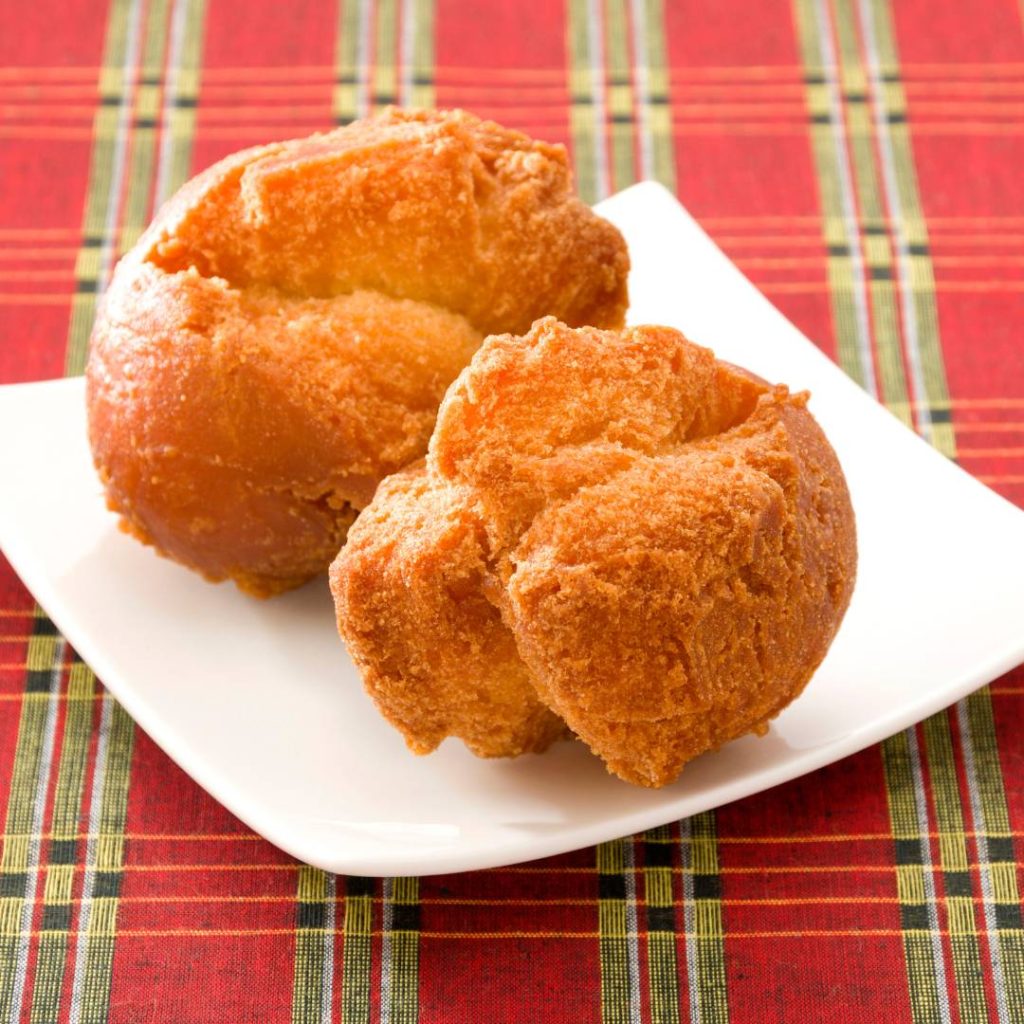 Two okinawa fried doughnuts on a white plate.