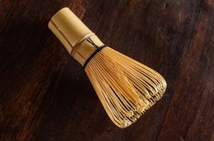 A bamboo whisk on a wooden table.