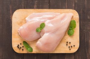 Two chicken breasts on a safest cutting board for chicken.