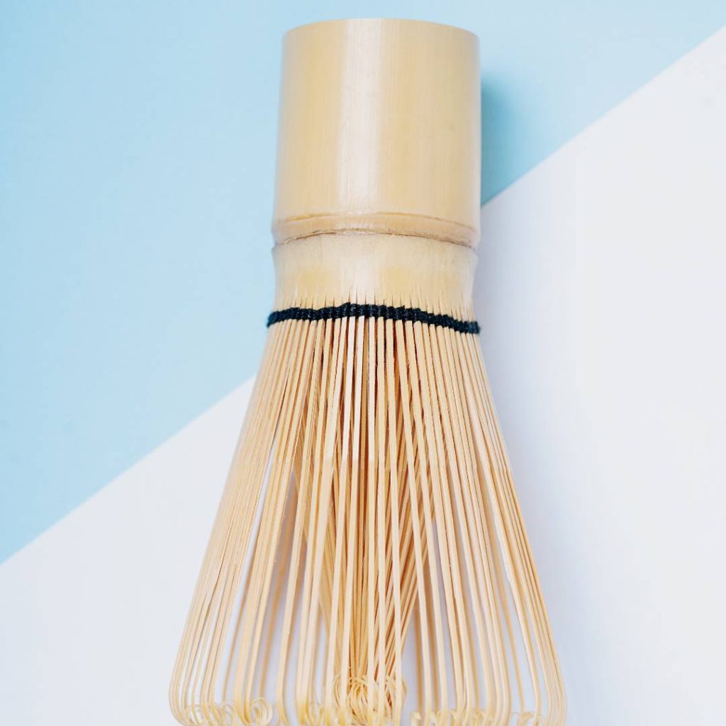 A matcha whisk on a blue and white background.