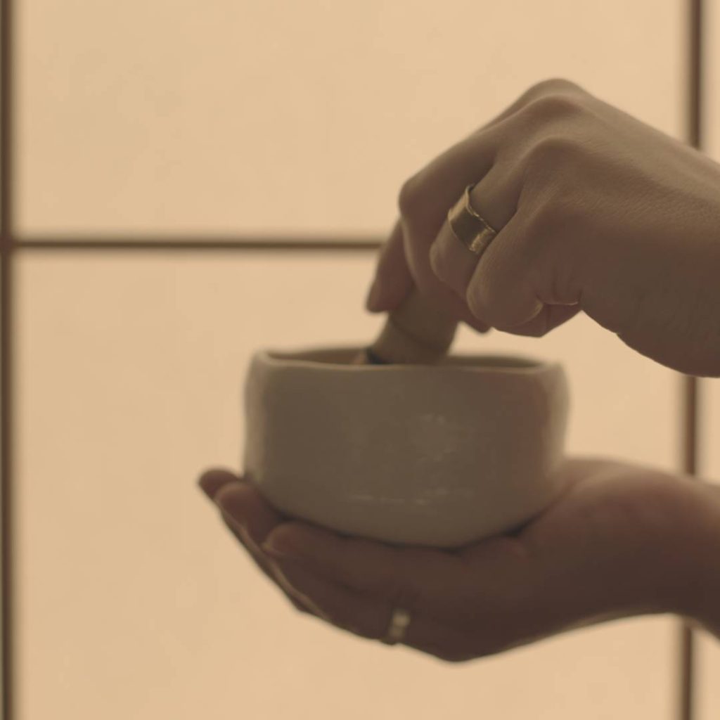 A woman's hand is holding a bowl of matcha tea.