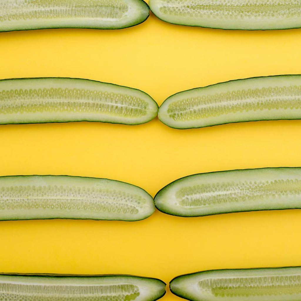 Sliced cucumbers for sushi on a yellow background.