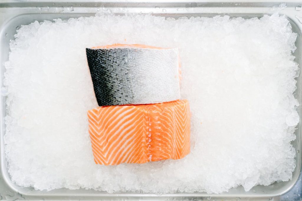 Sushi grade salmon fillets on ice in a silver tray.