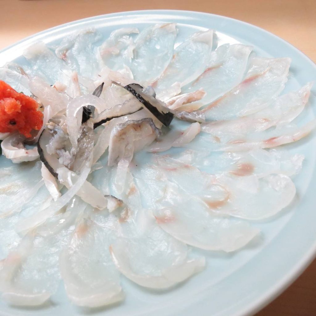 A plate of sashimi from Osaka is sitting on a table.