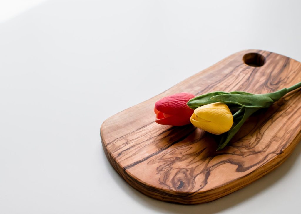 An image of a hand gently scrubbing a natural wood cutting board with a mixture of coarse salt and lemon juice, removing stains and odors