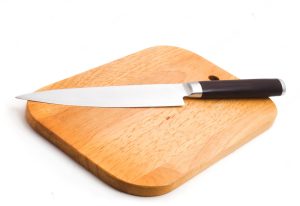 A knife on a wooden cutting board on a white background.