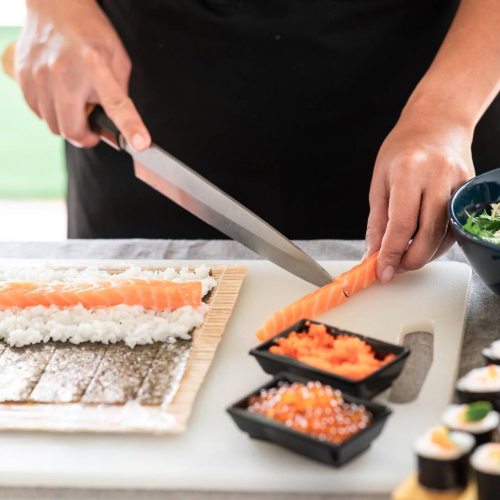 A person cutting salmon for sushi.