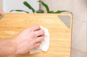 Man wiping cutting board with a cloth showing what to do before using wood cutting board