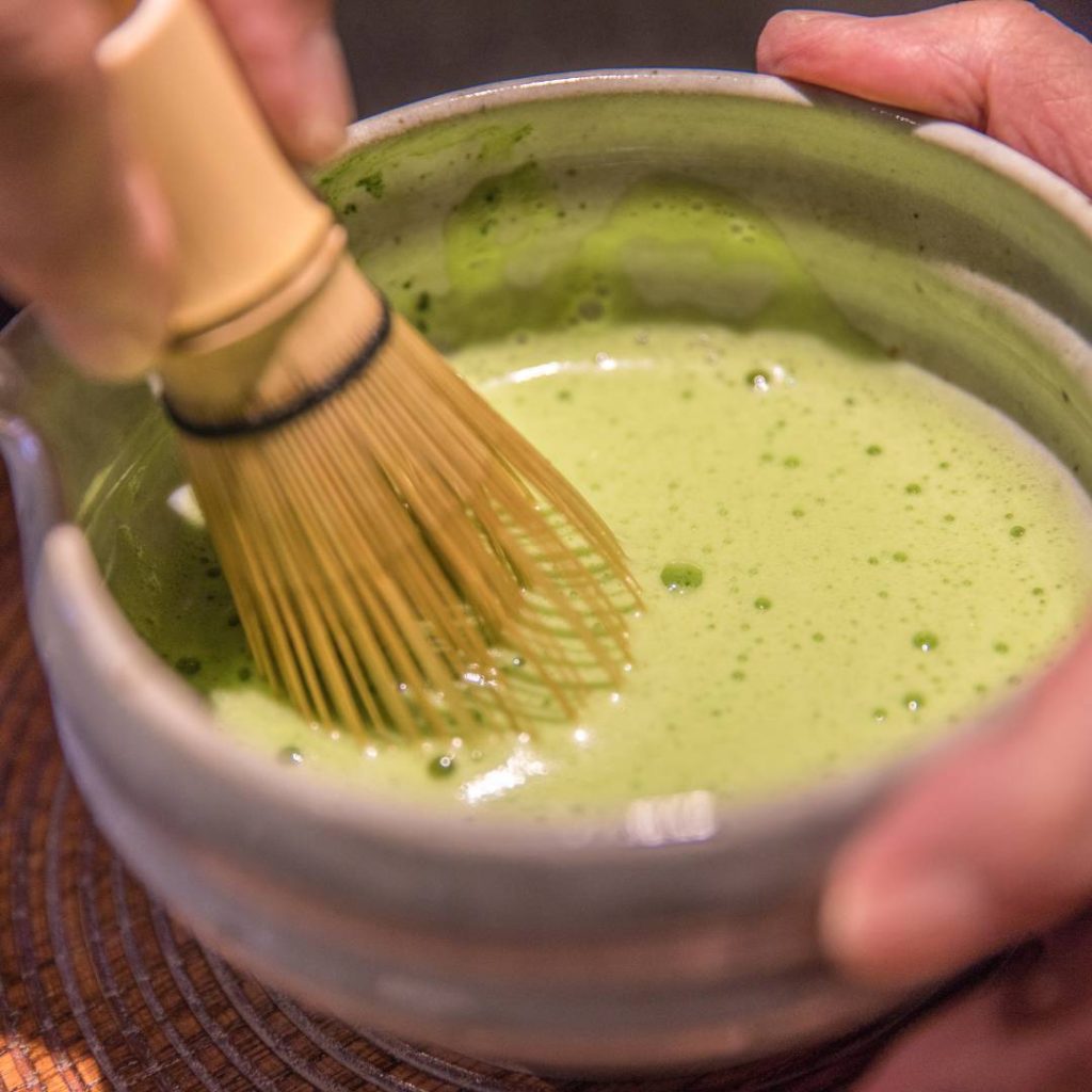 A person from Kyoto is pouring green tea into a bowl.