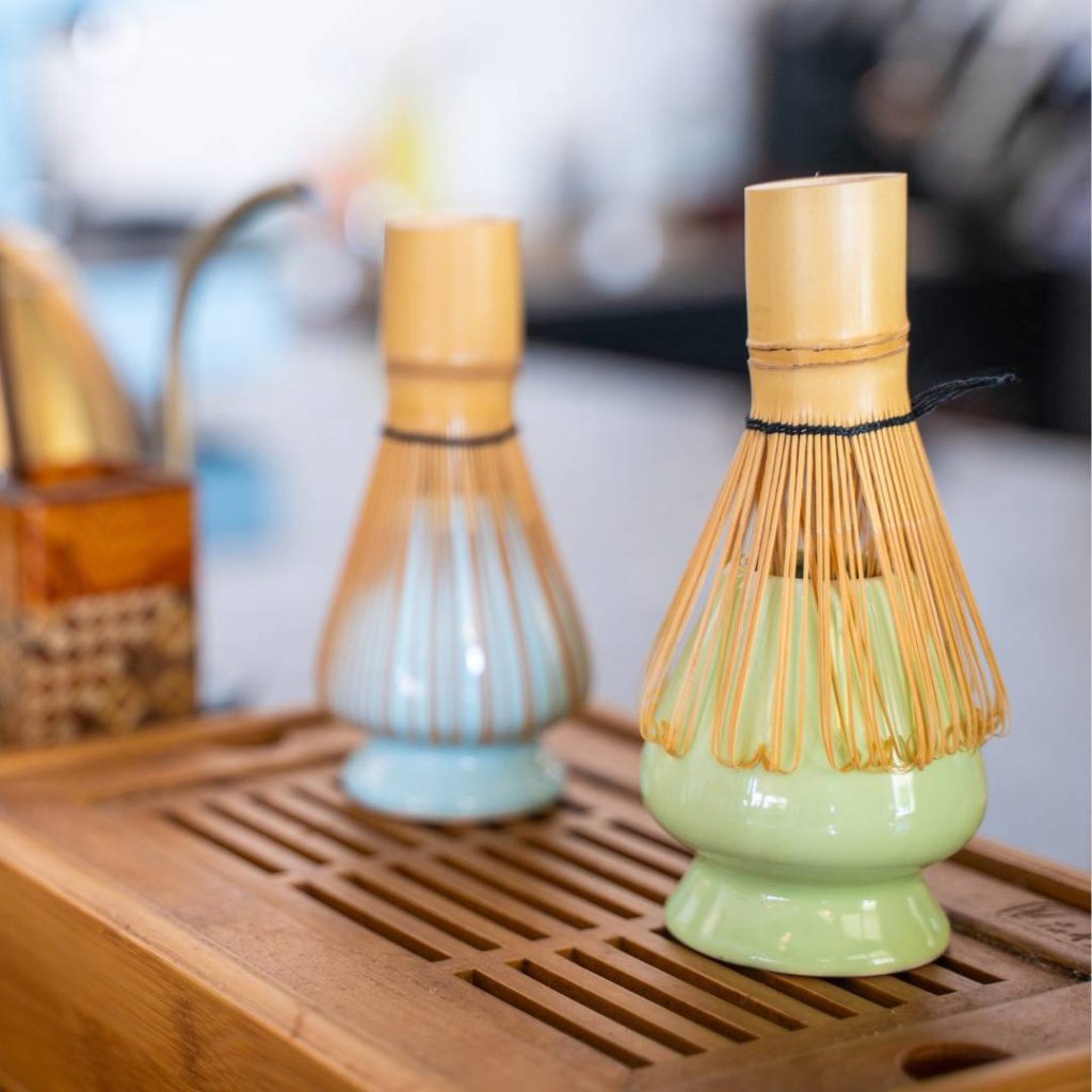 Two bamboo whisks neatly stored on a wooden tray.