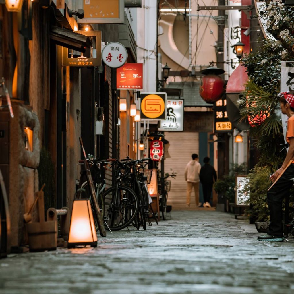 A man is walking down a cobblestone street in Osaka.