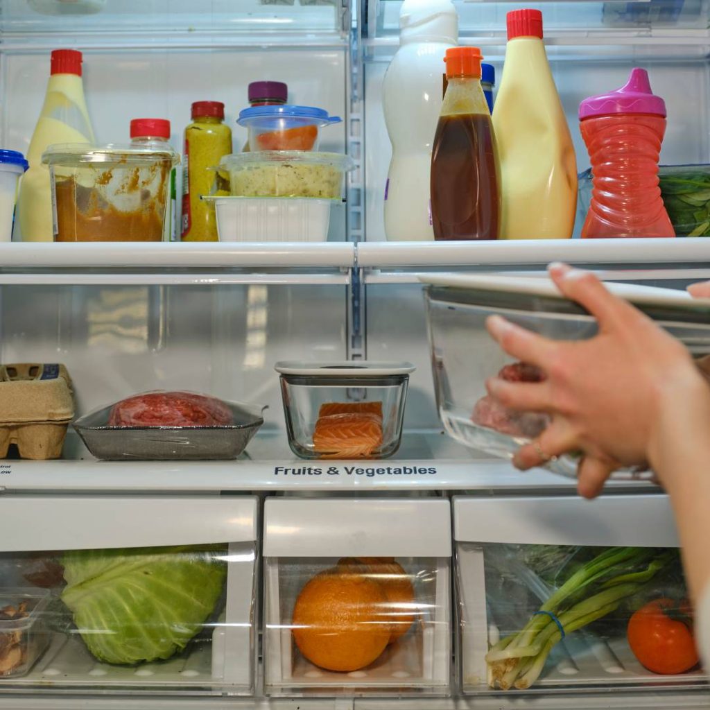 A person is putting sushi into a refrigerator.