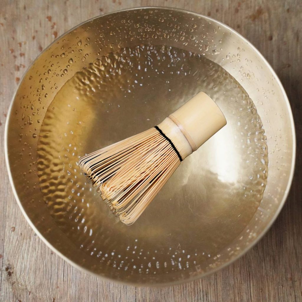 A bowl with a bamboo whisk, illustrating how to revive a matcha whisk effectively.