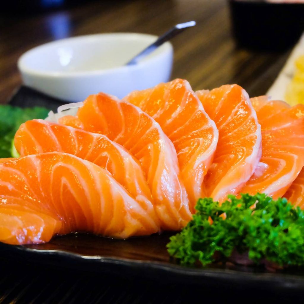 A piece of sushi-grade salmon is sitting on a black plate.