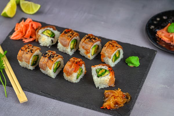 Sushi without mat on a slate plate with chopsticks.