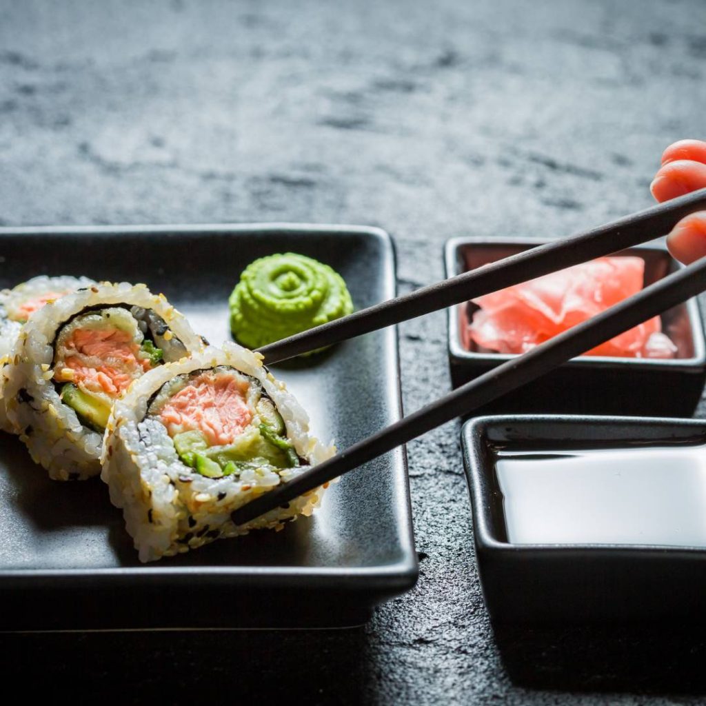 Sushi rolls with wasabi, radish and soy sauce neatly arranged on a plate.