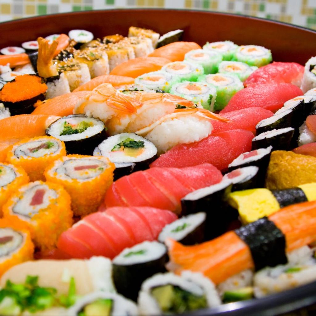 A plate with numerous sushi rolls on it.