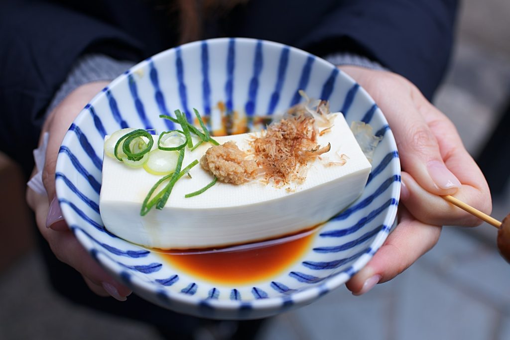 A person holding a bowl of tofu in Kyoto.