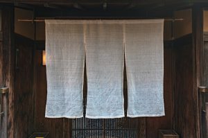 Japanese curtains hanging on a wooden door with a Noren curtain rod.