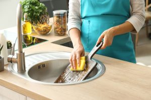 A woman cleaning the safest cutting board for chicken in kitchen sink.