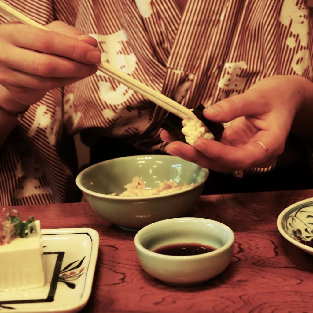 A Japanese man puts rice on a seaweed wrap before eating it.