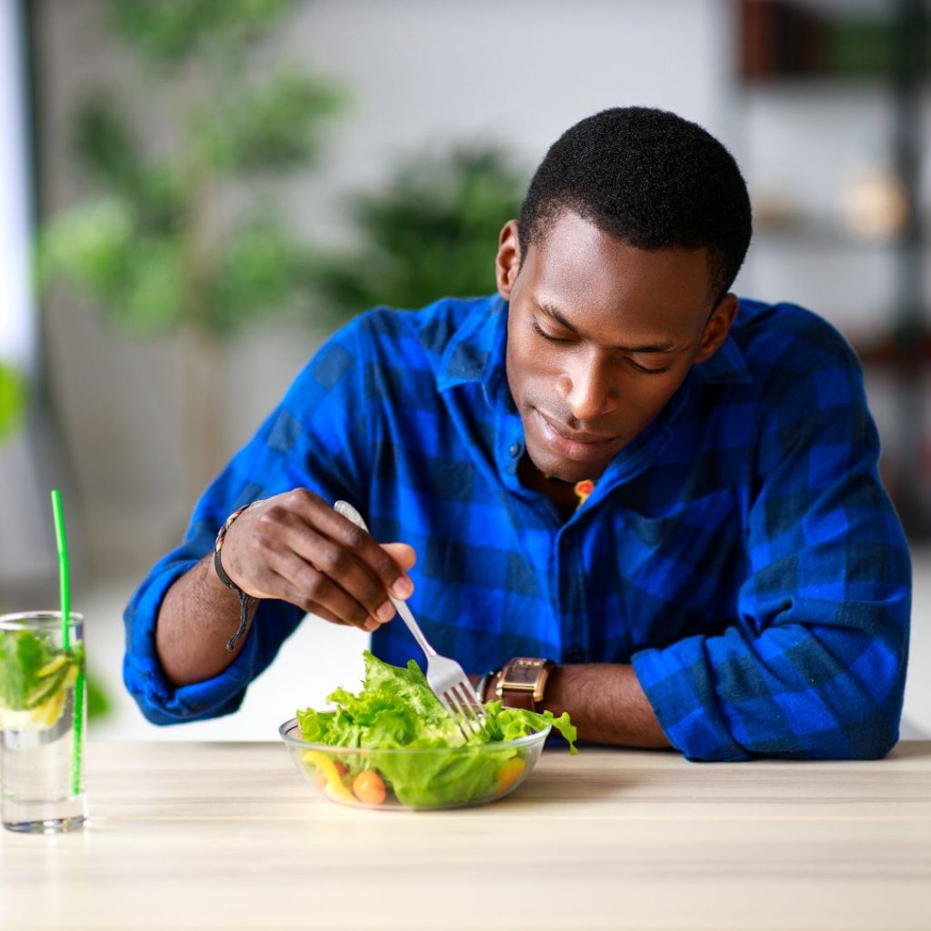 A man eats a bowl of salad.