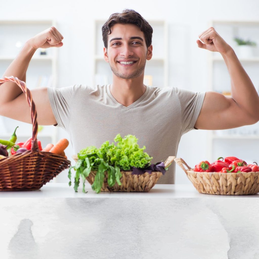 A man flexes his biceps in front of a basket of fruits.